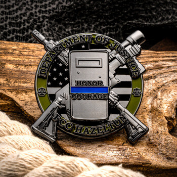 Custom Department of Justice FCC Hazelton challenge coin featuring a tactical shield, crossed rifles, and a thin blue line graphic on a rustic wood background.