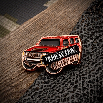 Red off-road vehicle lapel pin featuring the text Redacted and Operation Stryke Out.