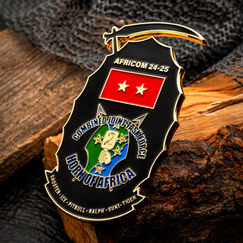 Shield-shaped AFRICOM 24-25 challenge coin featuring Combined Joint Task Force - Horn of Africa emblem with two white stars on a red background.