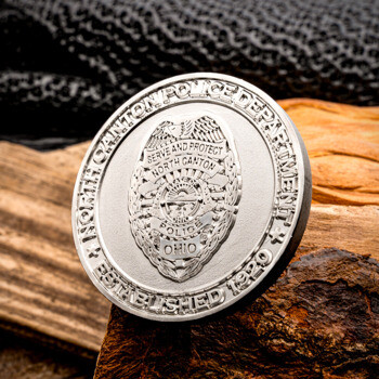 North Canton Police Department challenge coin with a detailed central badge design, displayed on a piece of natural wood bark.