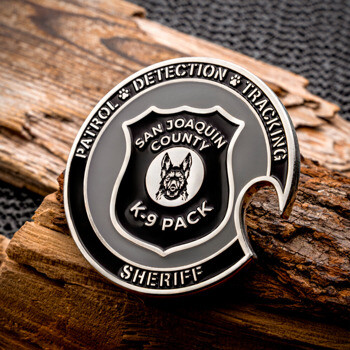 San Joaquin County Sheriff K-9 Pack challenge coin with black and silver enamel detailing, featuring a German Shepherd emblem, displayed on wood.