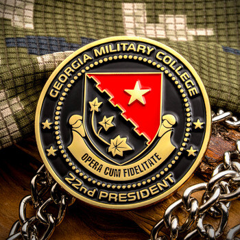 Georgia Military College 22nd President challenge coin featuring an enameled red and black shield emblem displayed over camouflage fabric.