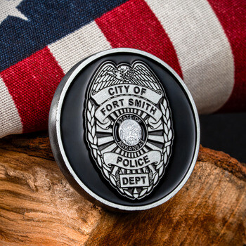 Fort Smith Police Department challenge coin with silver badge emblem on black enamel, displayed against an American flag.