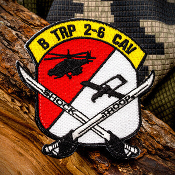 Embroidered military patch for B TRP 2-6 CAV Shock Troop featuring a helicopter, cavalry sabers, and shield design on wood and camouflage.