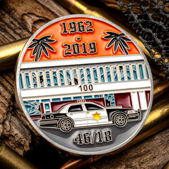 Challenge coin featuring a police cruiser parked in front of a building with palm trees and dates 1962 to 2019.