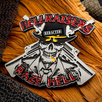 Custom challenge coin shaped as a skeleton in a hat with crossed rifles, featuring text Hellraisers and Raze Hell.