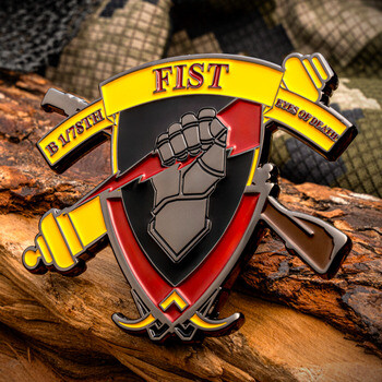 Custom military challenge coin shaped like a shield with crossed cannons, a gauntlet fist with lightning bolt, and FIST banner.