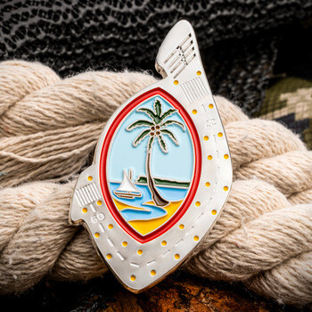 Guam seal shaped lapel pin with palm tree emblem resting on nautical rope and camouflage fabric