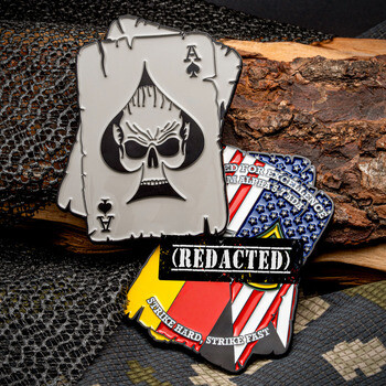 Playing card shaped challenge coin featuring an Ace of Spades skull and an American flag badge with REDACTED text.