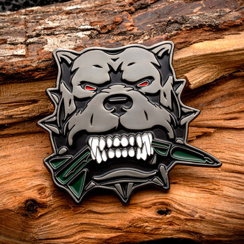 Enamel lapel pin depicting a growling grey bulldog with red eyes biting a broken green arrow, set against rough wood.