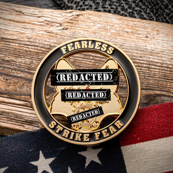 Cutout challenge coin featuring Fearless Strike Fear text and cutout dog head silhouette resting on wood and an American flag