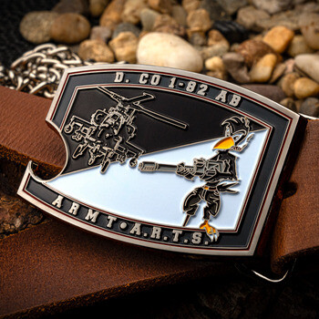 Custom military belt buckle featuring an attack helicopter, cartoon mascot, and text D. CO 1-82 AB ARM T.A.R.T.S. on a brown leather strap.