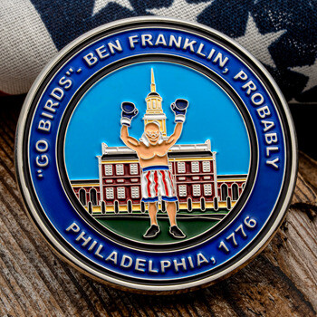 Challenge coin featuring Ben Franklin as a boxer in front of Independence Hall with text reading Go Birds and Philadelphia 1776 on an American flag.