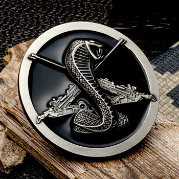 Round challenge coin featuring a silver cobra snake over crossed rifles on a black recessed background.