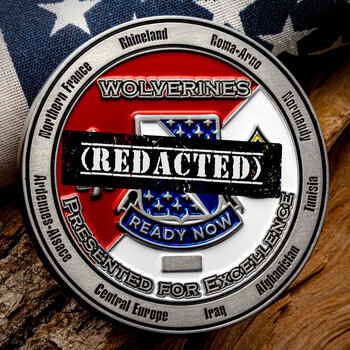 Military challenge coin with Wolverines inscription, campaign honors along the rim, and an American flag pattern in the center.