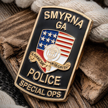 Smyrna GA Police Special Ops shield-shaped challenge coin with American flag badge emblem on rustic wood and rope.