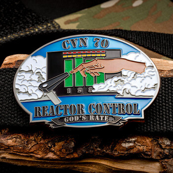 Oval belt buckle design challenge coin for CVN 70 Reactor Control featuring a control console panel and clouds against a blue background.