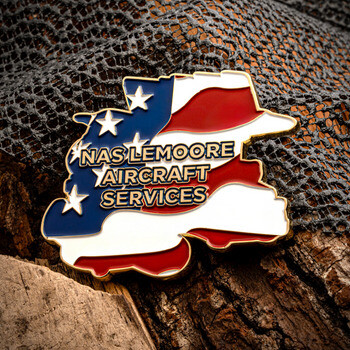NAS Lemoore Aircraft Services custom lapel pin shaped like a state with American flag design and gold trim on wood texture.