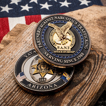 Partners Against Narcotics Trafficking law enforcement challenge coin displayed on weathered wood with an American flag background.